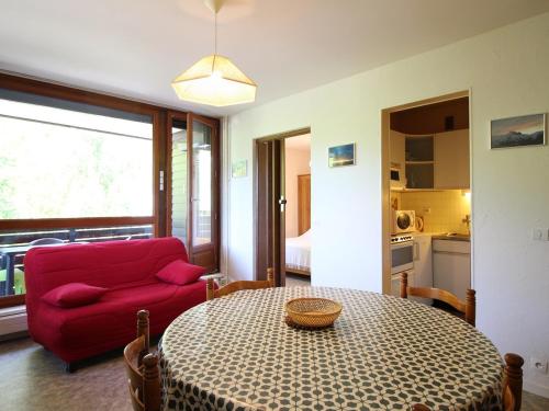 un salon avec une table et un canapé rouge dans l'établissement Mont-Dore: T2 avec Balcon et Garage privé - FR-1-608-133, à Le Mont-Dore