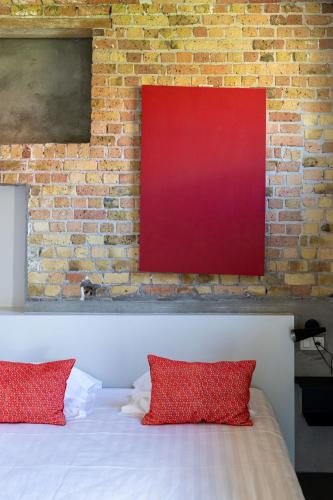 a bed with red pillows in front of a brick wall at Groot Noordhof in Nieuwpoort