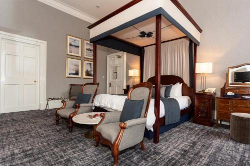 ein Hotelzimmer mit einem Himmelbett und Stühlen in der Unterkunft Royal Scots Club in Edinburgh