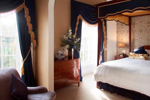 a bedroom with a canopy bed and a dresser and window at Royal Scots Club in Edinburgh