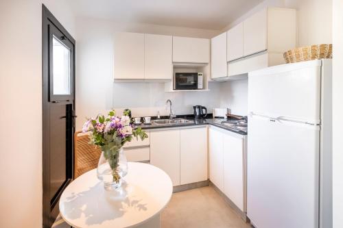 una cocina blanca con un jarrón de flores sobre una mesa en Top Rentals Brickell en Tigre