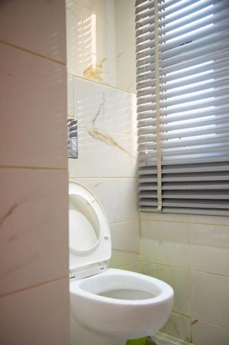 a bathroom with a white toilet and a window at IMOLEASE Kouessi Menontin in Cotonou