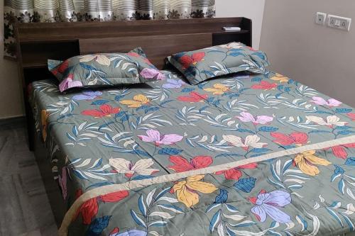 海得拉巴的住宿－2 BHK Fully Furnished in Kukatpally #201，一张带花卉棉被和两个枕头的床