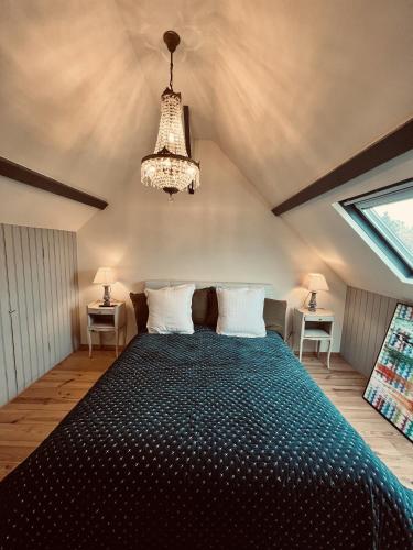 - une chambre avec un grand lit et un lustre dans l'établissement Ailleurs sous les étoiles, à Manneville-la-Raoult