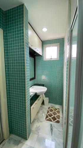 a bathroom with green tiled walls and a sink at Embassy Home KLCC Jalan Ampang in Kuala Lumpur