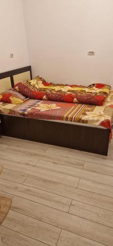a bed sitting in a room with a wooden floor at Apartament Militari Residence in Roşu