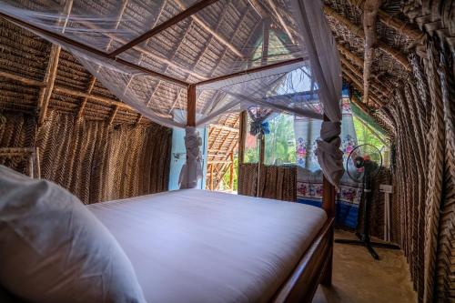 a bed in a thatched room with a window at Paje Beach Bandas in Paje
