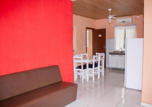 a kitchen and a dining room with a red wall at Residencial Havaí in Guaratuba