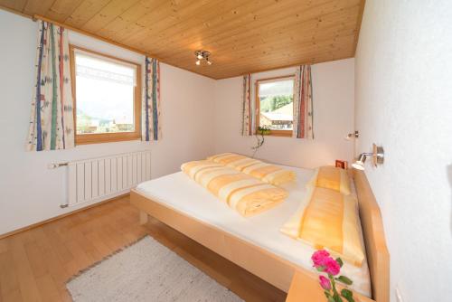 1 Schlafzimmer mit einem großen weißen Bett und 2 Fenstern in der Unterkunft Appartement Moosbrugger Haus Elisabeth in Schoppernau