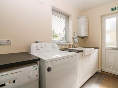 a white kitchen with a sink and a dishwasher at Berg Cottage in Ballindalloch