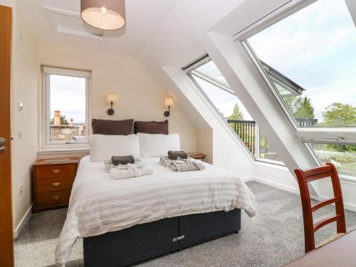a bedroom with a large bed and windows at Berg Cottage in Ballindalloch