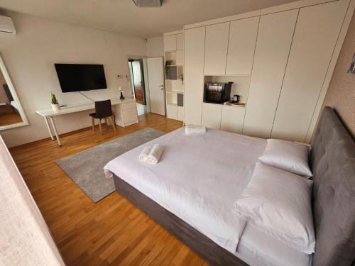 a bedroom with a large white bed and a desk at Comfort Rooms Remiza in Zagreb