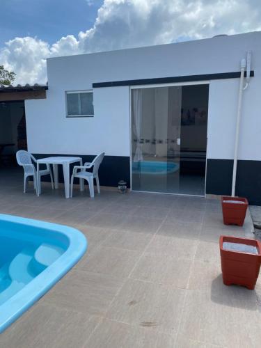 a patio with a table and chairs next to a swimming pool at Suítes Jasmim in Prado