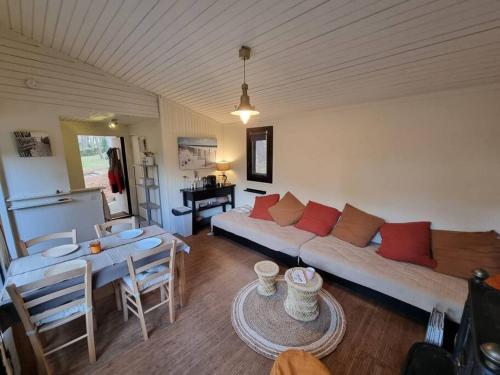 un salon avec un canapé et une table dans l'établissement Charmant cottage dans les pins, entre océan & golf, à Lacanau