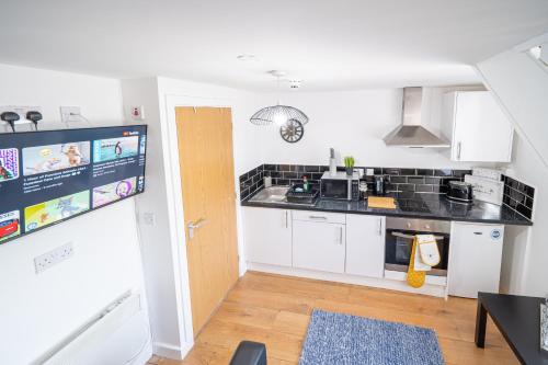 una cocina con armarios blancos y encimeras negras en Bv Kirkstall Central 1 Bedroom Apt Free Private Parking, en Leeds