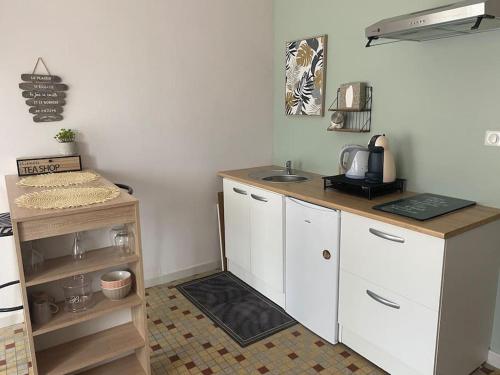 une cuisine avec des armoires blanches et un comptoir dans l'établissement L’évidence…., à Flavigny-sur-Moselle