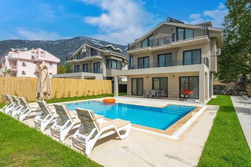 a house with a swimming pool and some chairs at Villa Lina Ölüdeniz/Fethiye in Fethiye