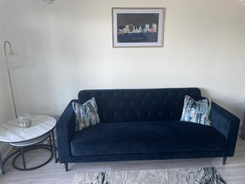 a blue couch in a living room with a table at Lux Lisburn Road, Belfast in Belfast