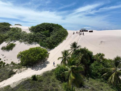 un grupo de personas caminando por una playa de arena en Pousada o Forte, en Mangue Seco