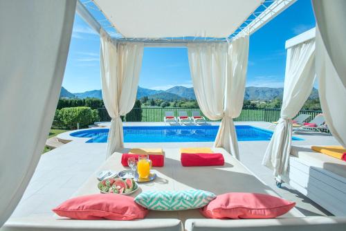 ポリェンサにあるOwl Booking Villa Siquier - Luxury Retreat with Mountain Viewsのベッド1台、テーブル、プールが備わる客室です。