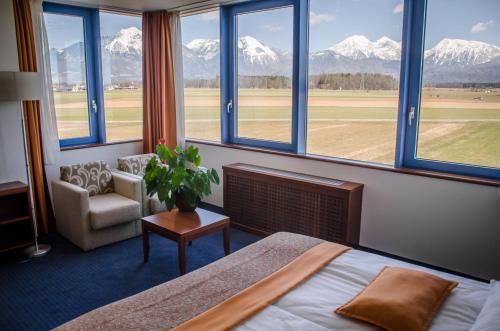 - une chambre avec un lit, une chaise et des fenêtres dans l'établissement Garni Hotel Azul, à Kranj