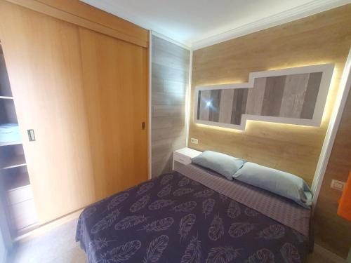 a bedroom with a bed and a wooden wall at 5 Salou,Playa,Piscina cento PARKING in Salou