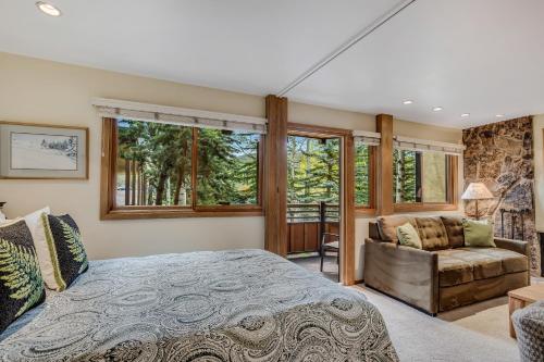 a bedroom with a bed and a couch and windows at Laurelwood Condominiums 207 in Snowmass Village
