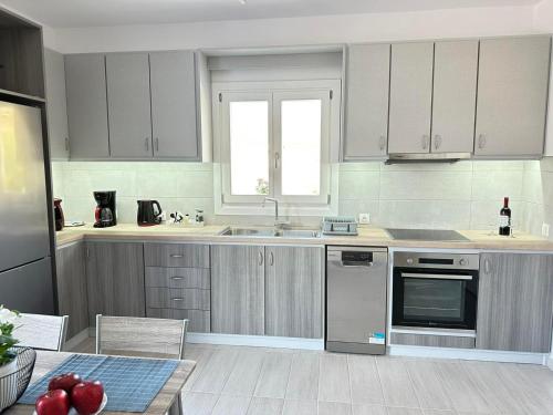a kitchen with white cabinets and a sink at Leo House Kea in Korissia