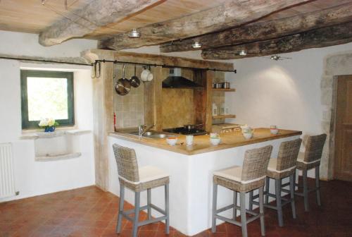 - une cuisine avec un bar, des chaises et un évier dans l'établissement Le Chateau de Pervinquieres, à Ginals