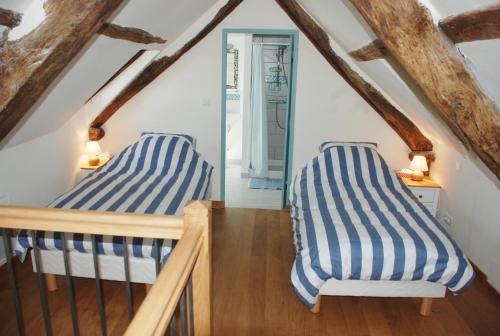 Cette chambre mansardée comprend 2 lits et des poutres apparentes. dans l'établissement Le Chateau de Pervinquieres, à Ginals