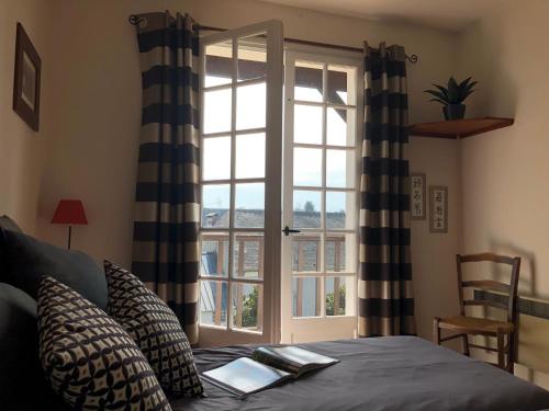 a bedroom with a bed and a window with a book on it at Les Hortensias in Espoey