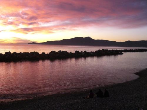 two people sitting on the beach at sunset at Chiavari Beach in Chiavari
