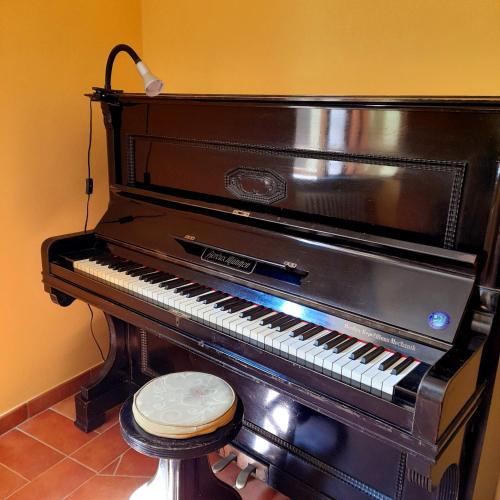 an old piano with a stool in a room at La casa in piazza in Panicale