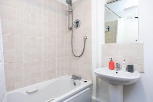 een witte badkamer met een wastafel en een bad bij Peaceful 1 bedroom apartment in Portobello, Dublin in Dublin