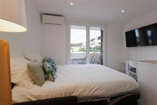 a white bedroom with a bed and a window at Studio Cosy Aigues Marines in Saint-Cyr-sur-Mer