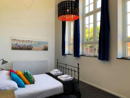 a bedroom with two beds and a chandelier at Bodham School Halls - 5 Bedrooms in Bodham