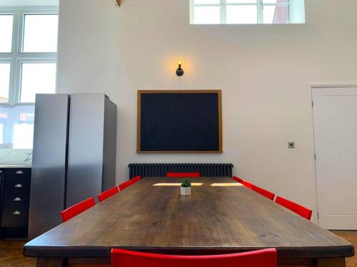 a conference room with a large wooden table and red chairs at Bodham School Halls - 5 Bedrooms in Bodham