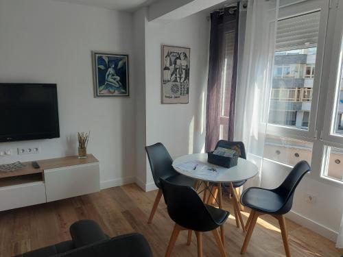 salon ze stołem, krzesłami i telewizorem w obiekcie Apartamento AIRES DEL NORTE, con WiFi gratis w mieście Santander