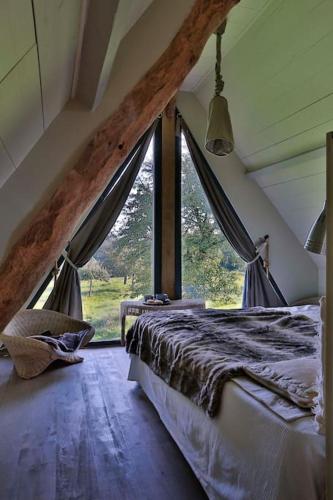 une chambre avec un lit et une grande fenêtre dans l'établissement COHCO'ART GITES, à Fatouville-Grestain