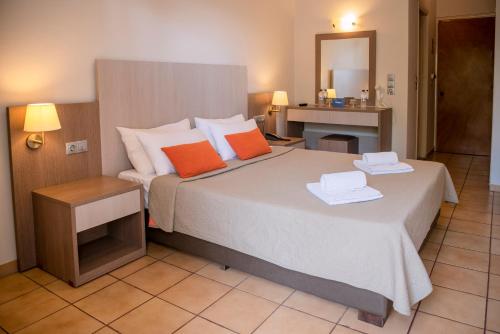 a bedroom with a large bed with two orange pillows at Kalloni Bay in Skala Kallonis