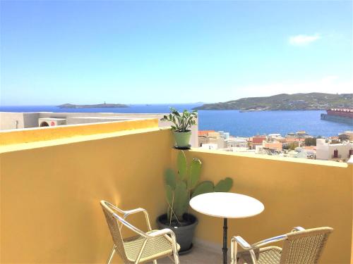 a table and chairs on a balcony with a view of the ocean at Pefkakia Park in Ermoupoli
