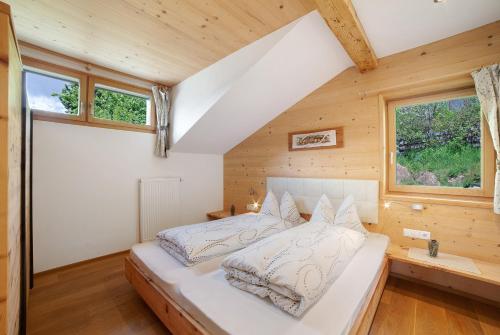 a bed in a room with wooden walls and windows at Oberhof Apt Nagelstein in Larcher