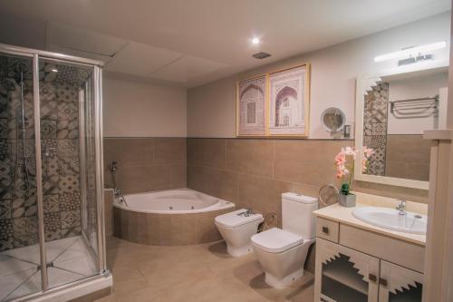 a bathroom with a toilet and a tub and a sink at Apartamentos Turísticos La Baílla in Rota