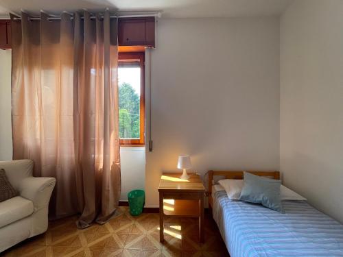 een slaapkamer met een bed, een stoel en een raam bij [come a Casa] da Marina in Pieve Vergonte