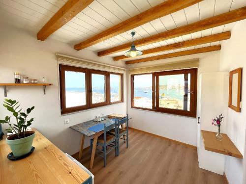 a living room with a table and chairs and windows at Pefkakia Park in Ermoupoli