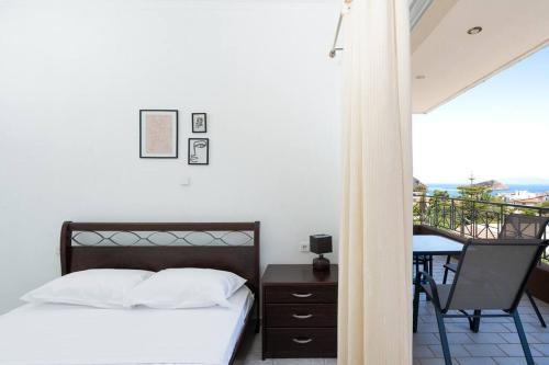 a bedroom with a bed and a table and a balcony at Omnia Maisonette by A&D Properties in Porto Rafti