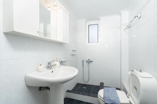 a white bathroom with a sink and a toilet at Omnia Maisonette by A&D Properties in Porto Rafti