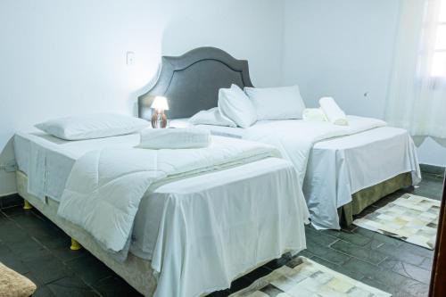 two beds in a room with white comforters at Pousada la colline in Santo Antônio do Pinhal