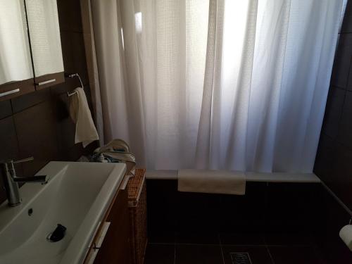 a bathroom with a white shower curtain and a sink at RVG Rania House with pool in Porto Heli