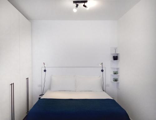 a white bedroom with a bed with a blue blanket at Al Pontile - by My Home In Como in Argegno